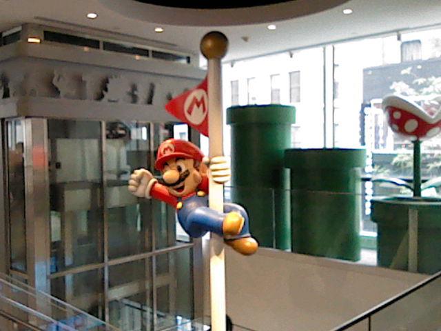 Mario cheerfully hangs off the edge of a flagpole at the Nintendo store in NYC. Shot on New 3DS XL.